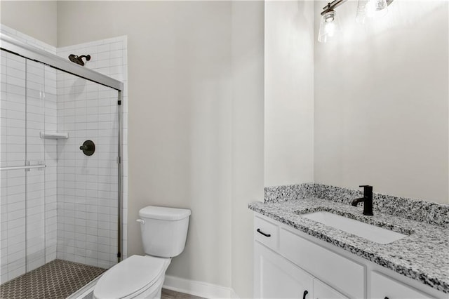 bathroom featuring vanity, a shower with shower door, and toilet