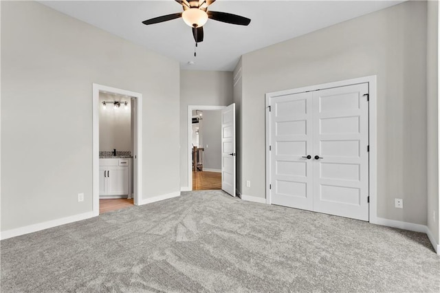 unfurnished bedroom featuring light carpet, connected bathroom, a closet, and ceiling fan