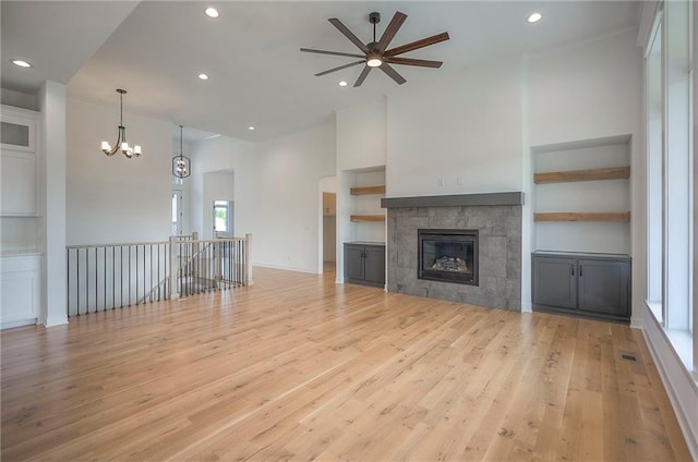 9000 N Clarion Ave, Kansas City, MO 64153 - unfurnished living room with ceiling fan, light wood finished floors, recessed lighting, a chandelier, and a tiled fireplace