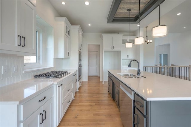 9000 N Clarion Ave, Kansas City, MO 64153 - kitchen featuring appliances with stainless steel finishes, a sink, light wood-type flooring, white cabinets, and pendant lighting