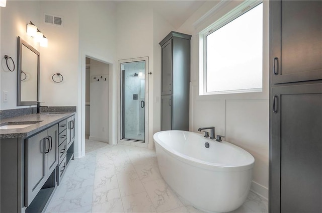 9000 N Clarion Ave, Kansas City, MO 64153 - bathroom featuring marble look tiles, double vanity, a freestanding bath, and a shower stall
