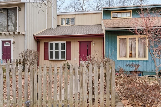 townhome / multi-family property with a fenced front yard and a shingled roof