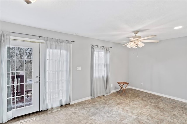 empty room featuring a ceiling fan, visible vents, baseboards, and light floors