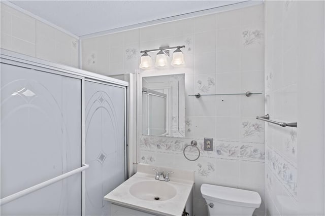 full bathroom with toilet, a shower with shower door, tile walls, and vanity