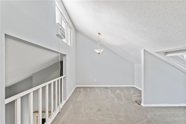 interior space with lofted ceiling, carpet, baseboards, and a textured ceiling