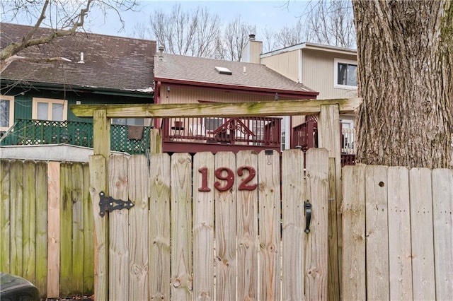 exterior space with a shingled roof, a chimney, and fence