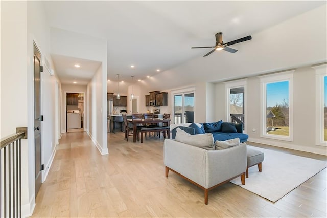 living room with ceiling fan, lofted ceiling, washer / clothes dryer, and light hardwood / wood-style floors