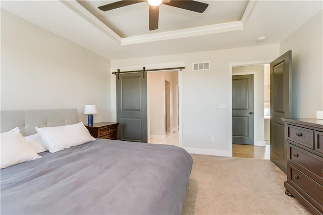 carpeted bedroom featuring a tray ceiling, a barn door, and ceiling fan