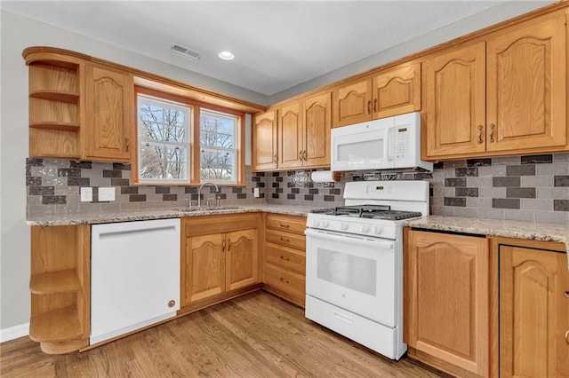 kitchen with light stone counters, white appliances, sink, and light hardwood / wood-style flooring