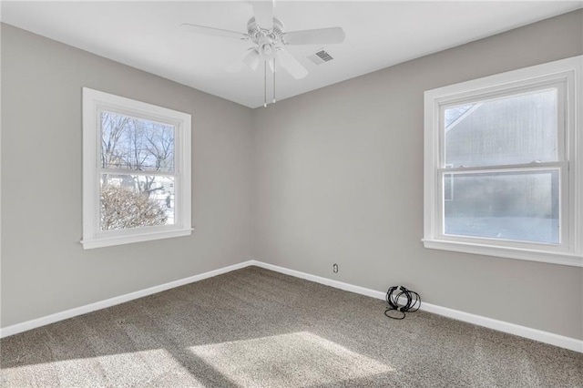 carpeted spare room featuring ceiling fan and a healthy amount of sunlight