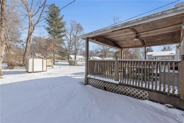 snowy yard with a wooden deck and a shed