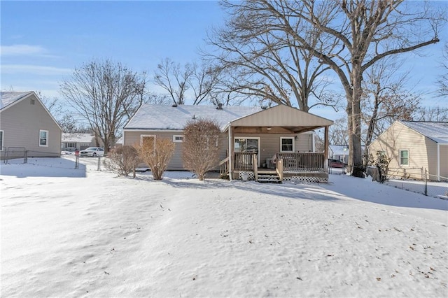 snow covered back of property featuring covered porch