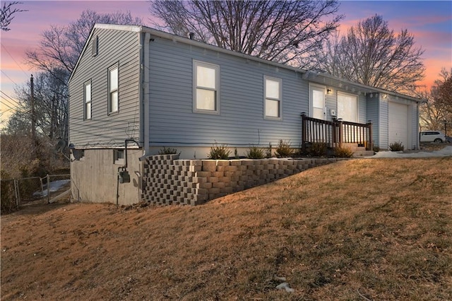 property exterior at dusk with a yard and a garage