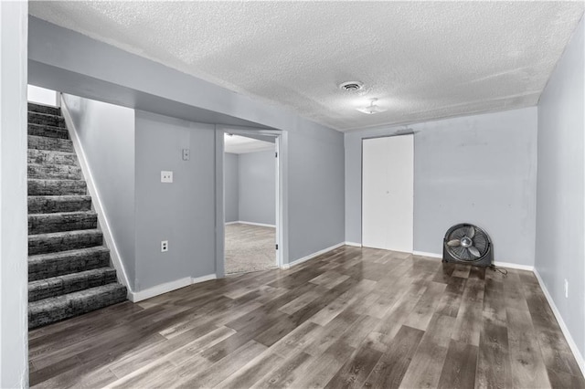 basement with a textured ceiling and dark hardwood / wood-style flooring