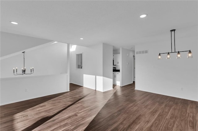 unfurnished room featuring an inviting chandelier and dark hardwood / wood-style flooring