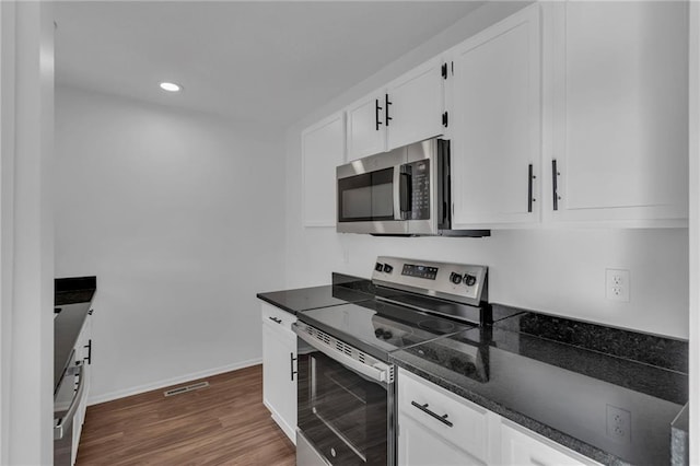 kitchen with white cabinetry, appliances with stainless steel finishes, dark hardwood / wood-style flooring, and dark stone counters