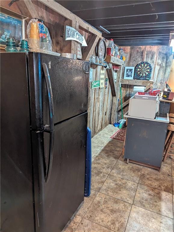 kitchen with wooden walls and black fridge