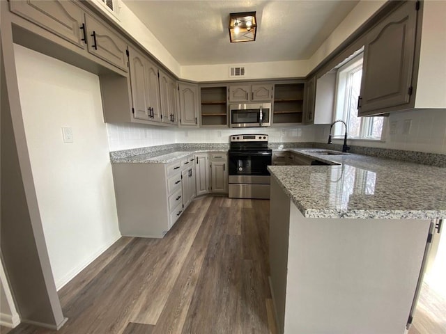 kitchen featuring dark hardwood / wood-style floors, sink, decorative backsplash, stainless steel appliances, and light stone countertops