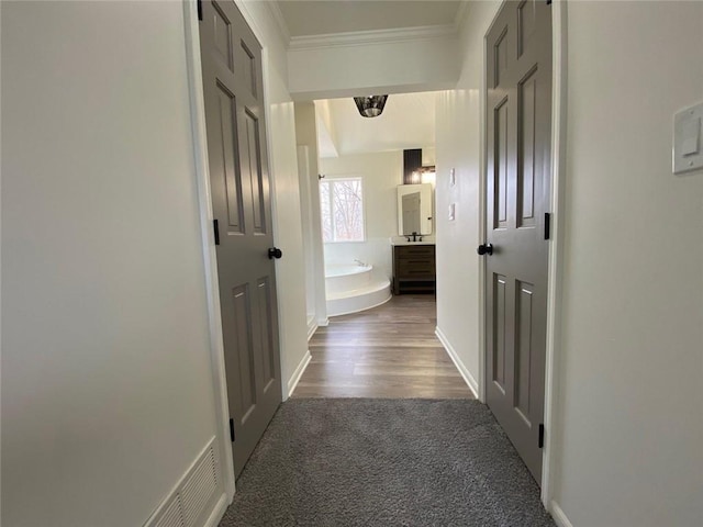 corridor featuring ornamental molding and dark carpet