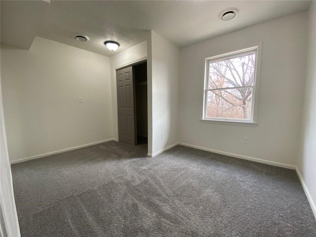 unfurnished bedroom with a closet and dark colored carpet