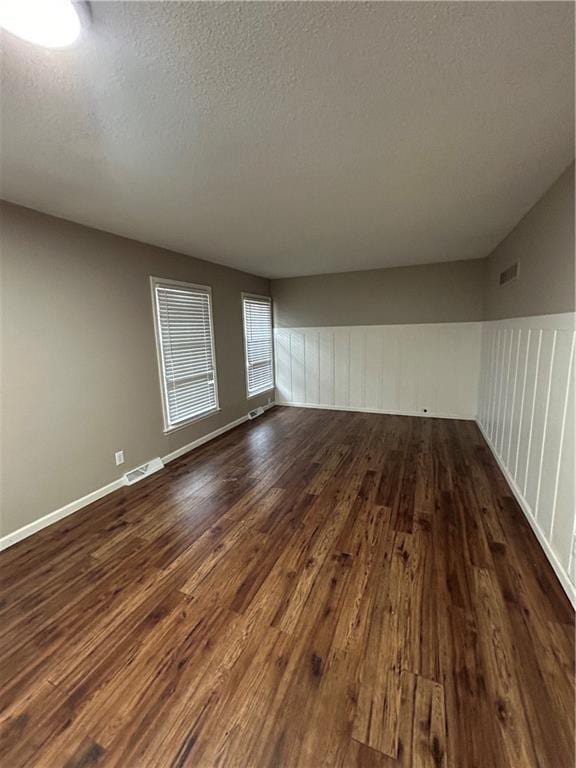 unfurnished room with a textured ceiling and dark hardwood / wood-style flooring