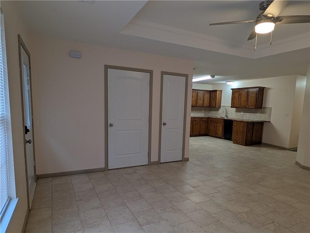 kitchen featuring sink, dishwasher, ceiling fan, backsplash, and a raised ceiling