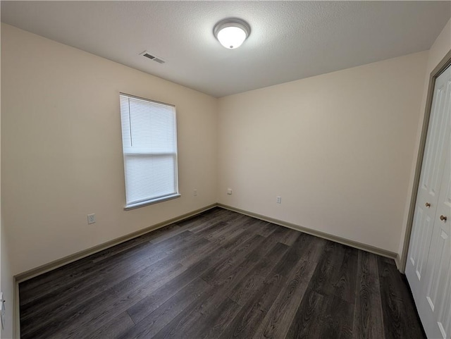 unfurnished room with dark hardwood / wood-style floors and a textured ceiling