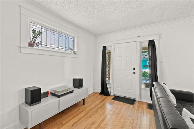 foyer entrance with crown molding, light hardwood / wood-style floors, a textured ceiling, and a wealth of natural light