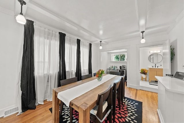 dining area with coffered ceiling, beam ceiling, and light hardwood / wood-style floors