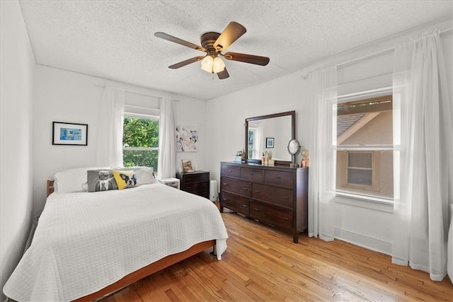 bedroom with ceiling fan, a textured ceiling, and light wood-type flooring