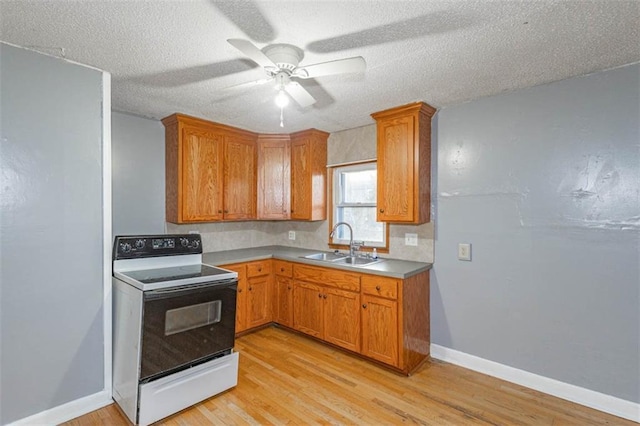 kitchen with electric stove, sink, light hardwood / wood-style flooring, and a textured ceiling