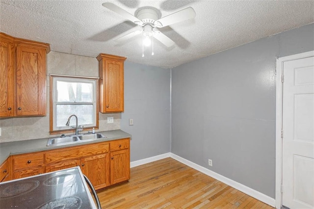 kitchen with sink, stainless steel range with electric cooktop, a textured ceiling, and light wood-type flooring