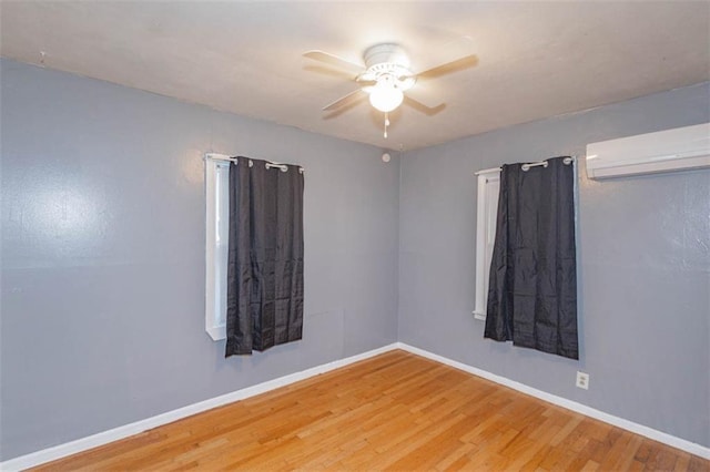 spare room featuring hardwood / wood-style floors, a wall mounted AC, and ceiling fan