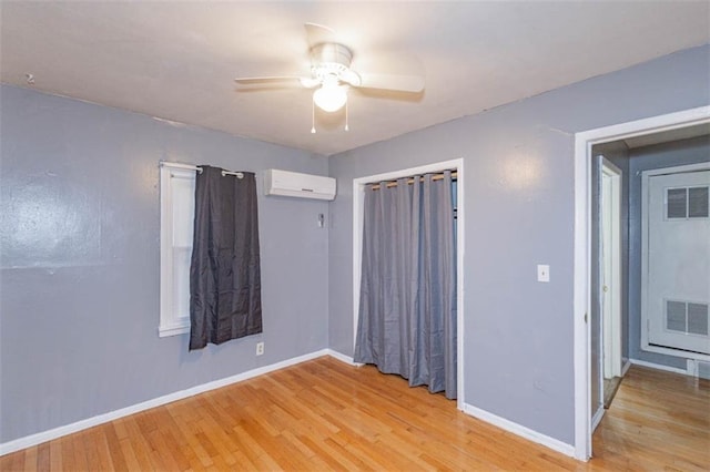 empty room featuring ceiling fan, a wall unit AC, and light hardwood / wood-style flooring