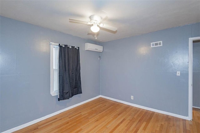 unfurnished room featuring a wall mounted AC, ceiling fan, and light hardwood / wood-style flooring