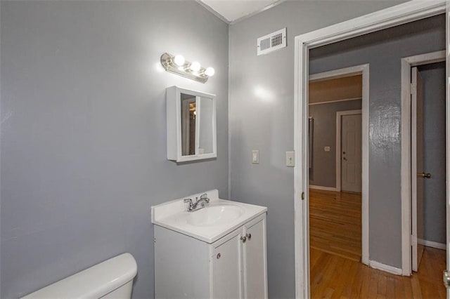 bathroom featuring vanity, wood-type flooring, and toilet