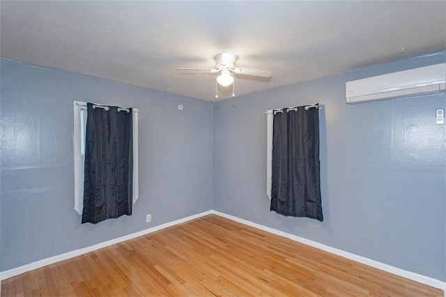 empty room with hardwood / wood-style floors, a wall mounted AC, and ceiling fan