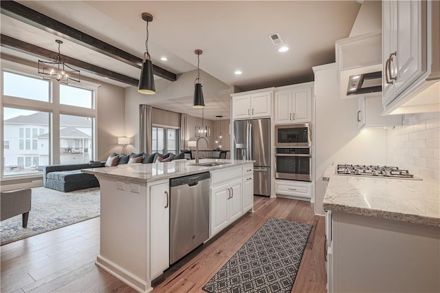 kitchen featuring stainless steel appliances, a kitchen island with sink, white cabinets, and light stone counters