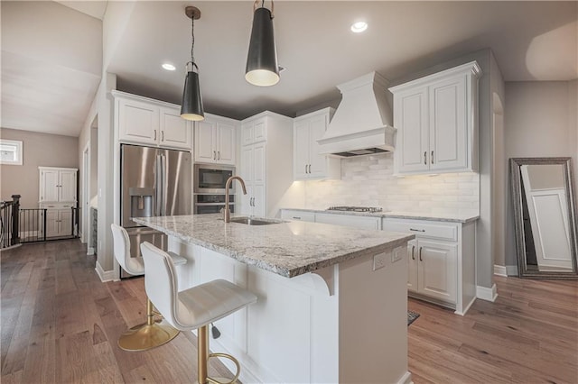 kitchen with white cabinetry, appliances with stainless steel finishes, and custom range hood