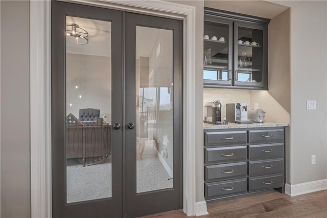 interior space featuring french doors, light stone countertops, dark wood-type flooring, and backsplash