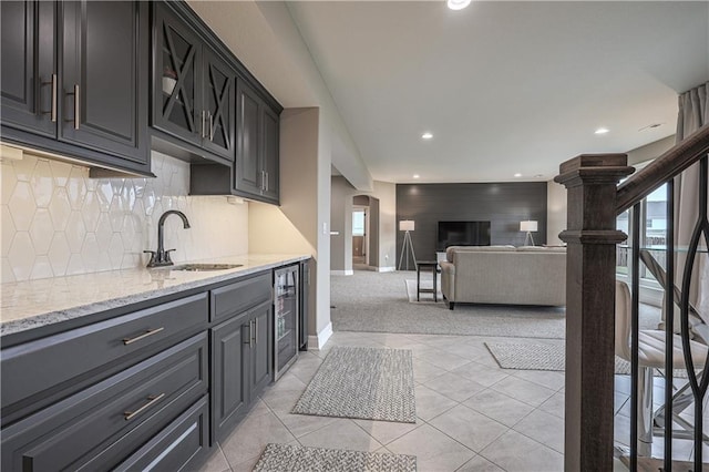 kitchen featuring light stone countertops, sink, a wealth of natural light, and wine cooler