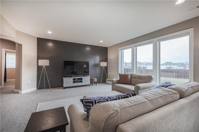 carpeted living room featuring wooden walls