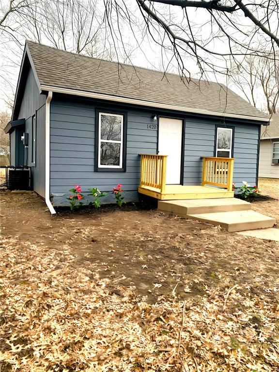 rear view of house featuring a shingled roof and cooling unit