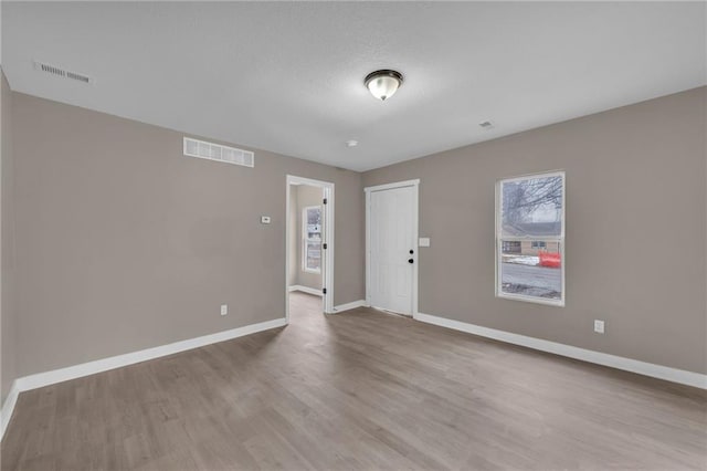 unfurnished room with wood finished floors, visible vents, and baseboards