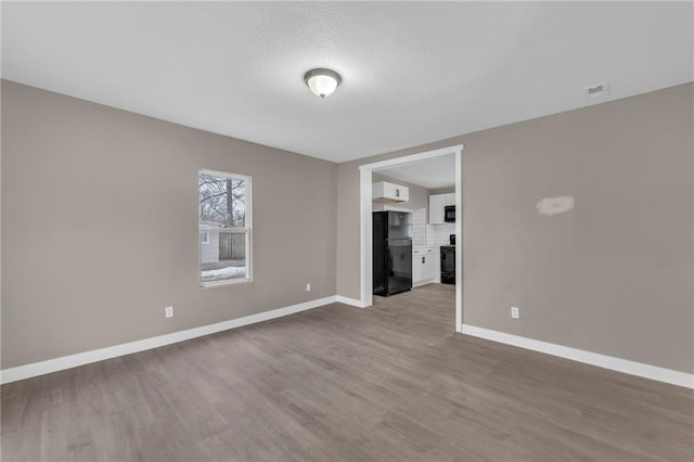 empty room with visible vents, baseboards, and wood finished floors