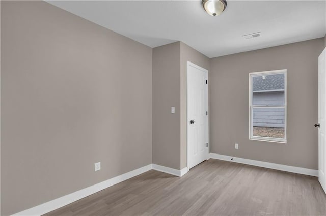 unfurnished room featuring visible vents, baseboards, and wood finished floors