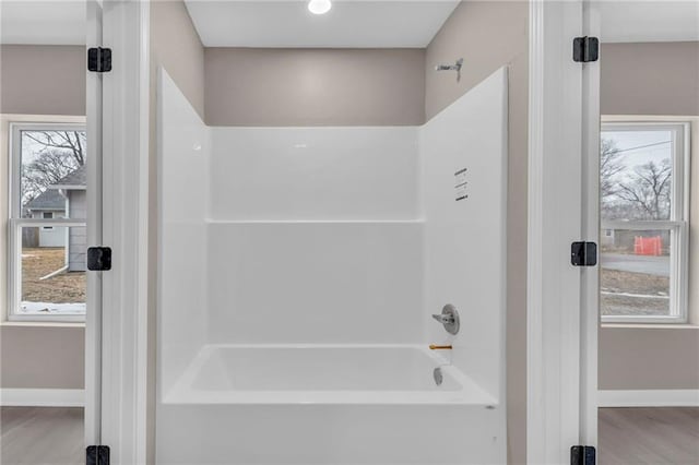 bathroom with shower / bathtub combination, wood finished floors, and baseboards