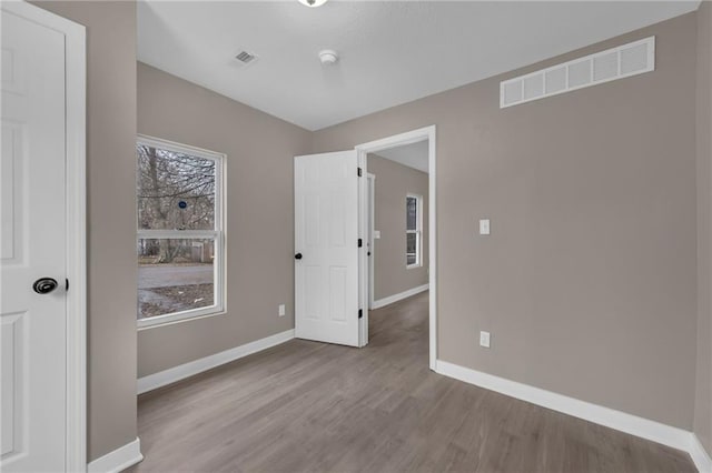 unfurnished bedroom with baseboards, visible vents, and wood finished floors