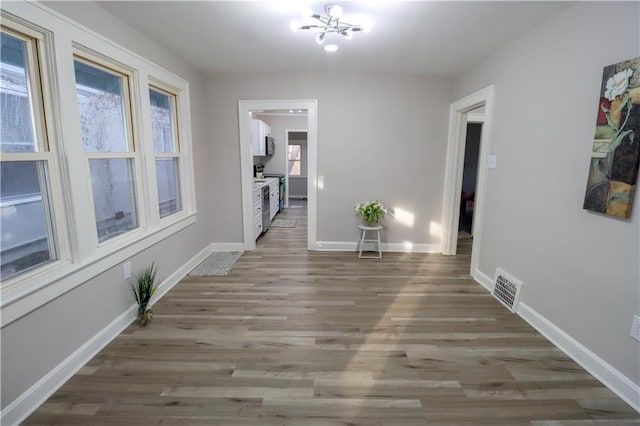 corridor with hardwood / wood-style flooring and a chandelier