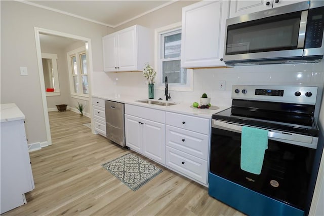 kitchen with sink, crown molding, light wood-type flooring, stainless steel appliances, and white cabinets